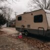 Travel trailer on a driveway in late autumn with RV antifreeze beside the water inlet